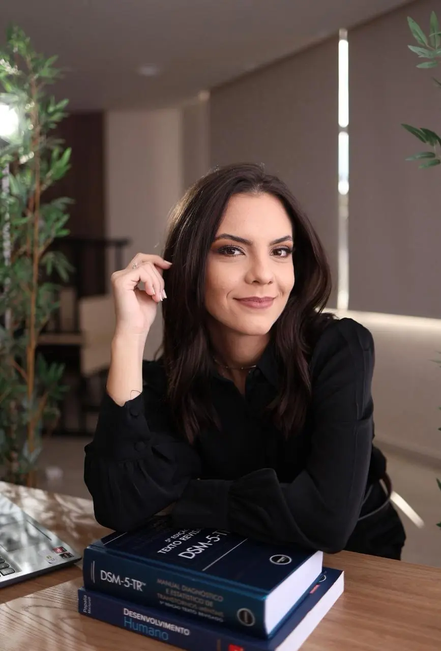 Júlia Sauer apoiada sobre livros em seu consultório